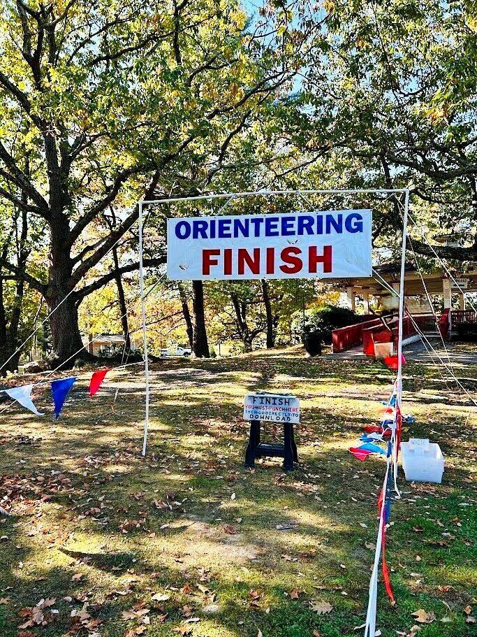 Ellice at the finish of an orienteering course, smiling, holding her placement ribbon